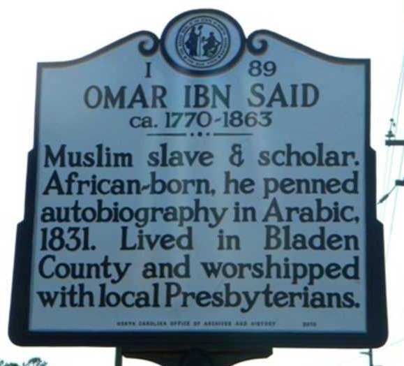 Image of historical marker for Omar Ibn Said.  "Muslim slave & Scholar.  African-born, he penned autobiography in Arabic, 1831. Lived in Bladen County and worshipped with local Presbyterians.